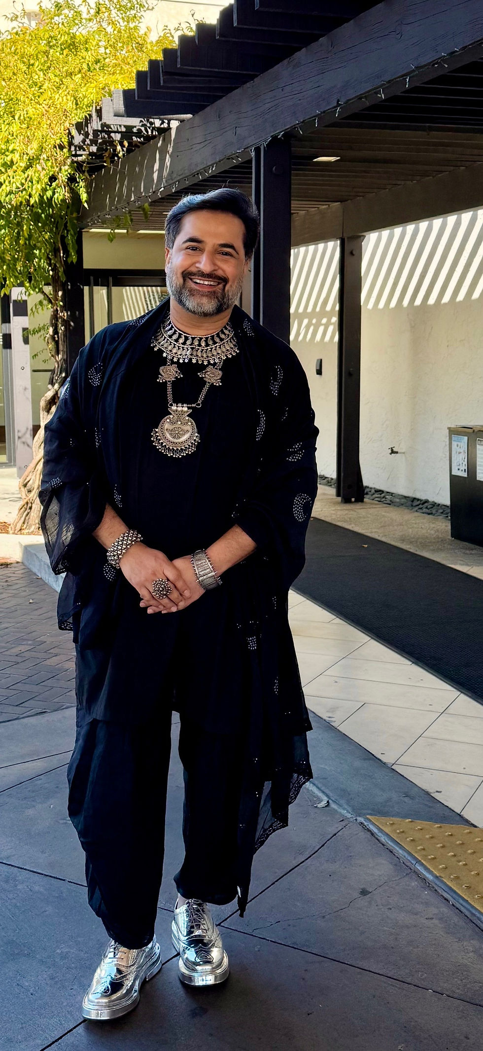 Suvir Saran in a gorgeous black outfit with silver jewelry and silver sneakers!