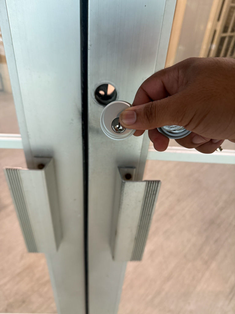 Locksmith installing a cylinder lock on commercial glass doors