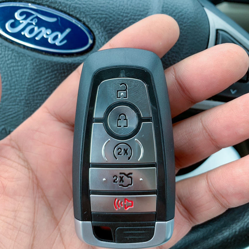 Hand holding a Ford car key fob with locksmith services.