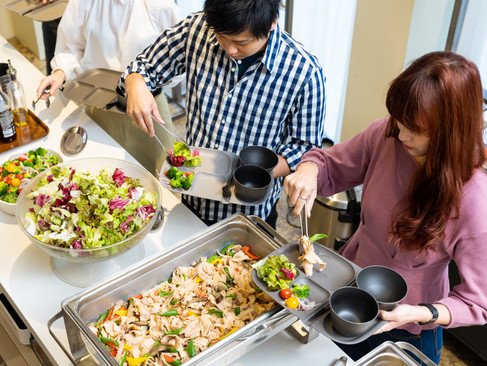 ランチをプレートに盛り付ける社員3名。