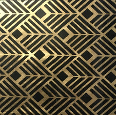 Decorative paint sample of symmetrical geometric shapes painted in black on a layer of gold leaf, creating a repeating diamond-like pattern. 