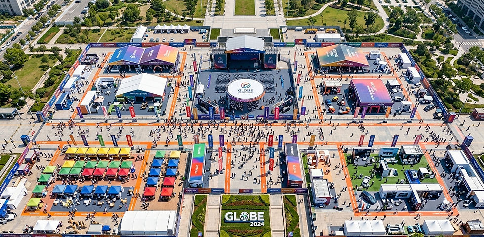 A high-angle, top-down aerial shot captures a sprawling corporate brand activation for "GLOBE 2024," utilizing professional drone photography for events. The image reveals a symmetrical layout of colorful branded tents, sponsor pavilions, and geometric walkways filled with attendees. This comprehensive perspective by DMA showcases the full scale of the venue infrastructure and crowd flow under bright, midday sunlight.