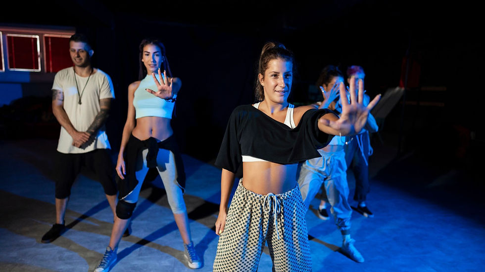 Grupo de pessoas a fazer zumba com um instrutor no palco, em ambiente corporativo.