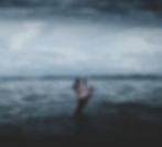 A hand reaching up from the lake water