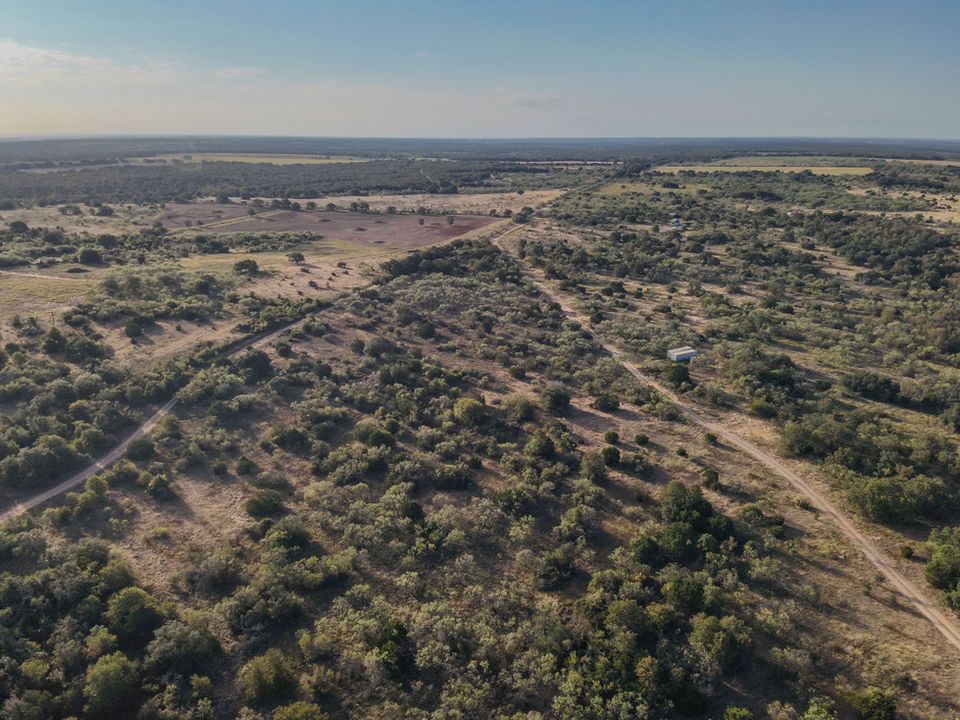 Wide aerial drone photo of a expansive North Texas ranch landscape with dirt roads