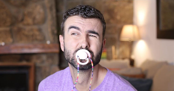 A bearded man with a pacifier in his mouth, illustrating the concept of infantilization—treating an adult as though they are still a child.
