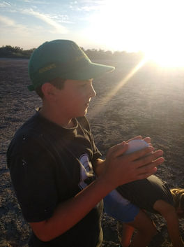 Niño mirando al atardecer, sosteniendo algo en sus manos