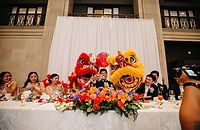Lion dancers performing beside a decorated banquet table at a wedding reception