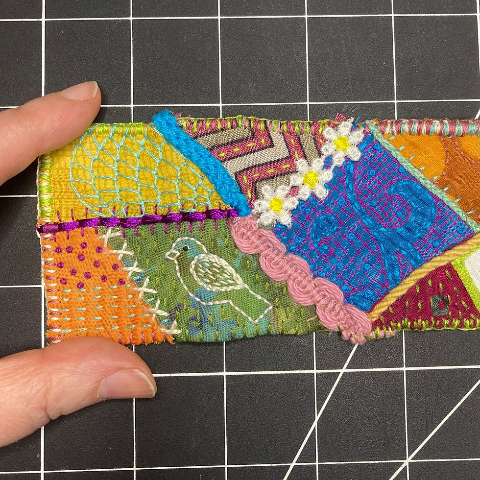 a completed crazy quilting scroll with a bird and a spider web