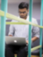 Man working on a laptop, surrounded by green and yellow structures.