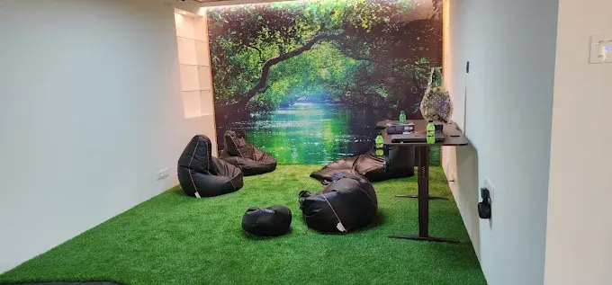 Relaxation area with bean bag chairs, green grass, and forest scene background.