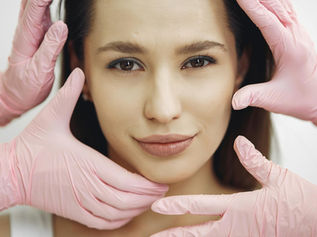 Gloved clinician's hands in a clinical setting, representing the medical device regulation behind dermal filler safety in the UK.