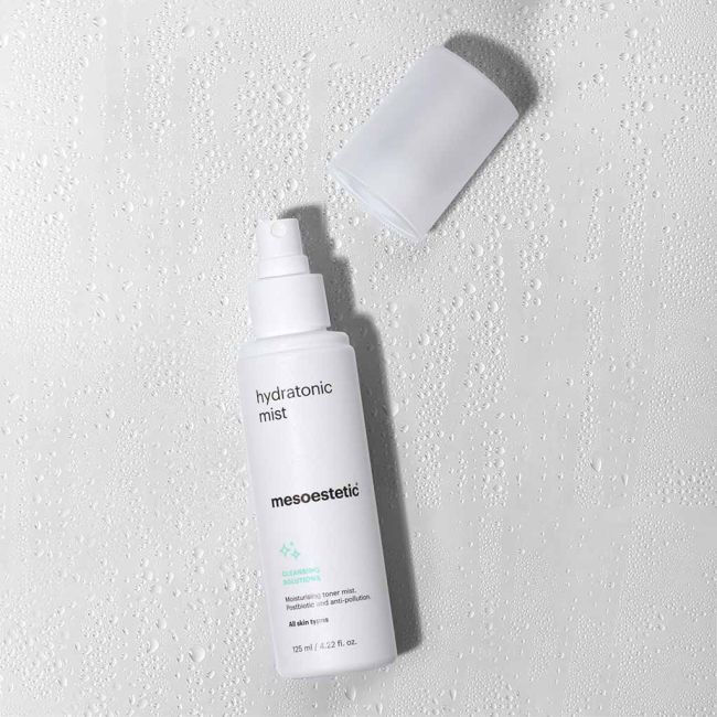 Thumbnail: White mesosestetic hyaluronic mist bottle and cap on wet white surface.