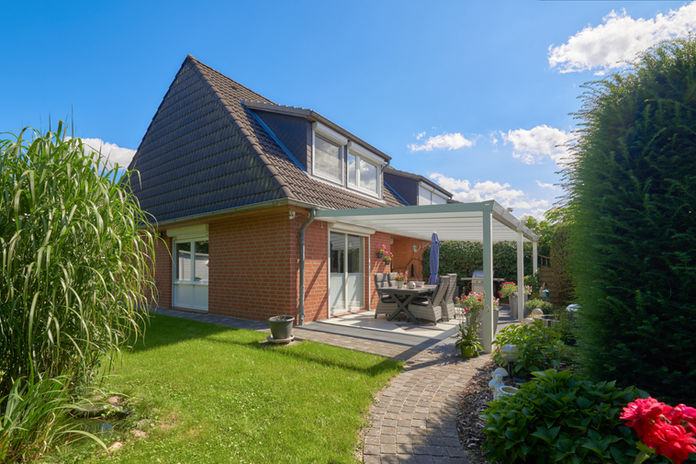 Außenaufnahme eines Reihenendhauses mit Garten und überdachter Terrasse.