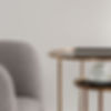 Close-up on modern gray armchair and two elegant, golden coffee tables with cup of coffee_