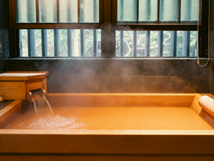 Cedar soaking tub filled with mineral-rich thermal water at a traditional Japanese onsen