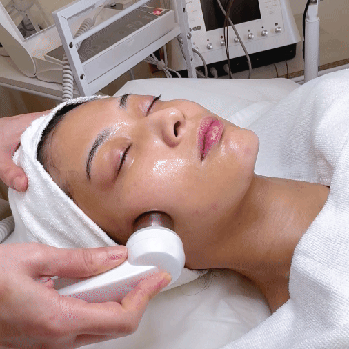 Woman undergoing a professional facial treatment with an electroporation probe enhancing serum absorption for deeper hydration and clear skin