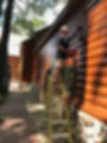 Man Painting Exterior of Log House