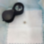 round diamond in a brifka next to a black jeweler's loupe