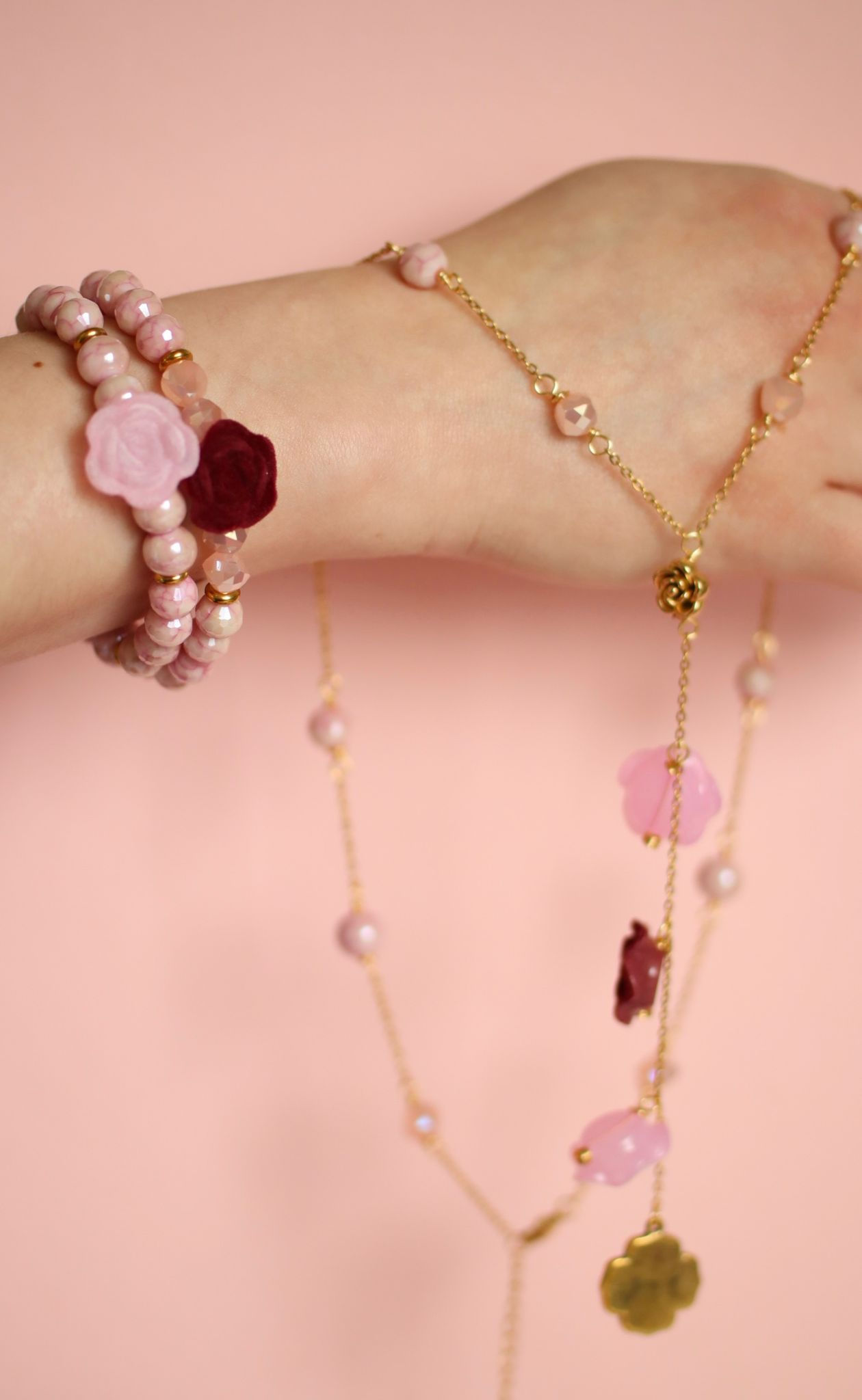 Woman wearing pink floral bracelet and matching rose necklace with gold stainless steel chain details.