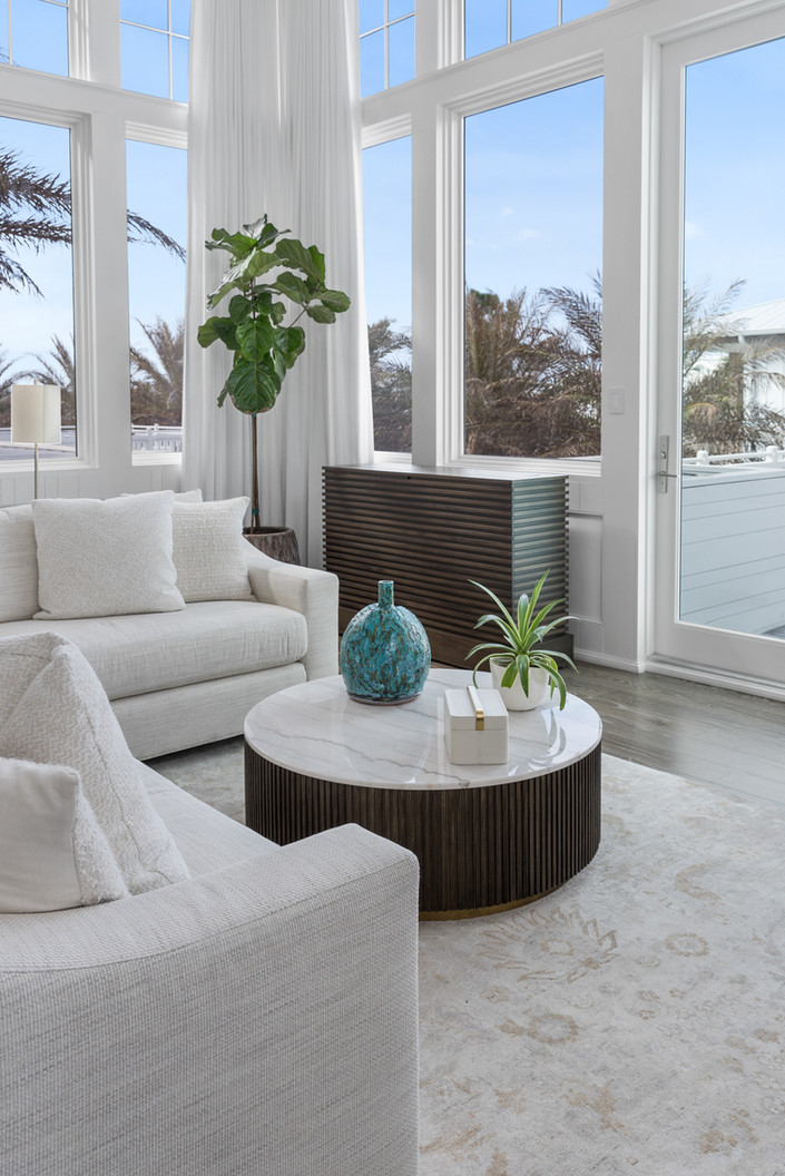 decorated small table surrounded by beautiful white couch and open windows