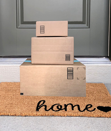 A stack of packages sitting on a door mat outside of a cozy home