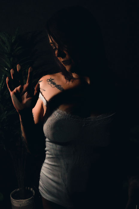 Silhouetted figure behind a steamy glass shower, water droplets creating an intimate and moody boudoir aesthetic.