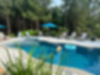 Eye-level view of a modern backyard pool with integrated natural stone and greenery