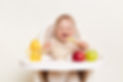 Baby wearing knitted sweater sitting in high chair and feels hungry, holding spoon and eat