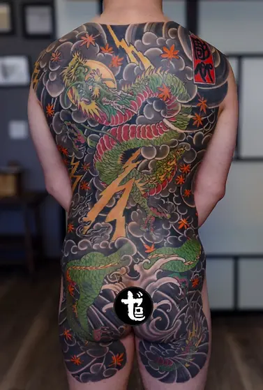Full back Japanese tattoo featuring a green dragon with lightning, maple leaves and waves, by Horipeppe Mukade | Genkoku Mukade at Zero One Ink in Sacramento, California.