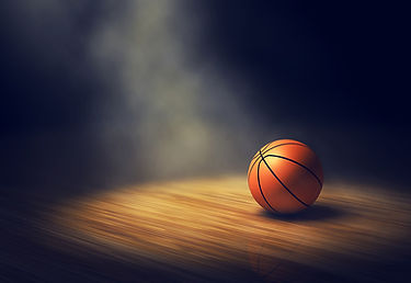 Basketball resting on hardwood basketball court