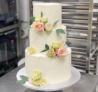 Three-tier white cake decorated with fresh flowers, handcrafted by Something Sigrid for a special occasion in Melbourne.