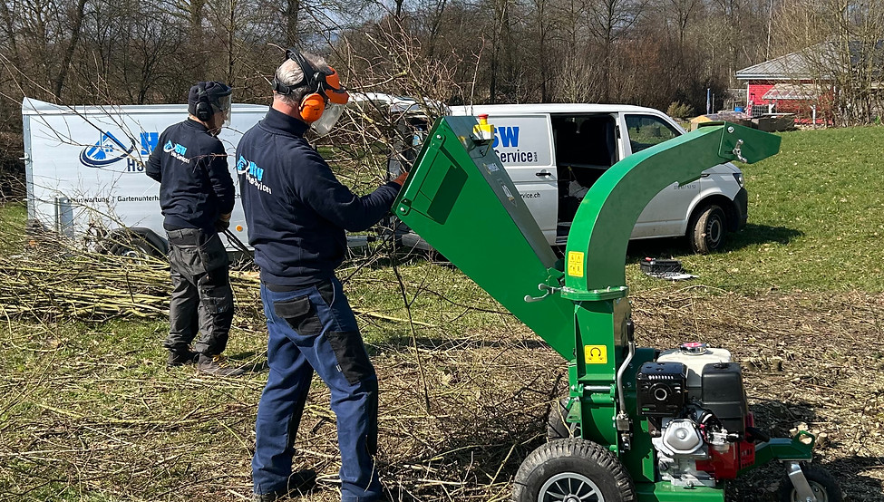 Hauswartung in Solothurn: Fachkräfte bei Gartenarbeiten mit Häcksler