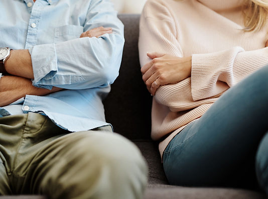 Paar mit jeweils verschränkten Armen auf dem Sofa