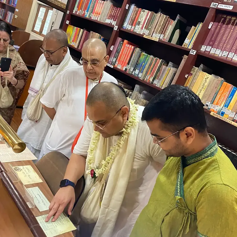 HG Prashant Mukund Das observing a rare manuscript at Bhaktivedanta Research Centre Kolkata on 11 April 2026, alongside devotees in a library filled with preserved Gaudiya Vaishnava scriptures.