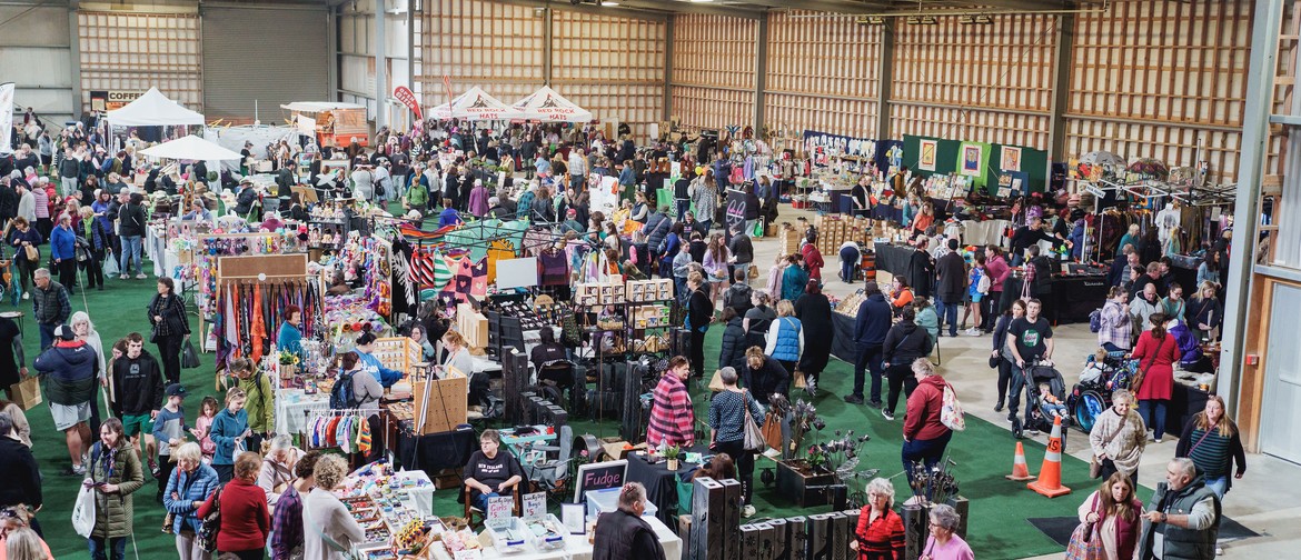 Busy indoor market with numerous people walking and shopping at stalls.