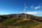 Wind turbines on green hills generating clean energy under blue sky.