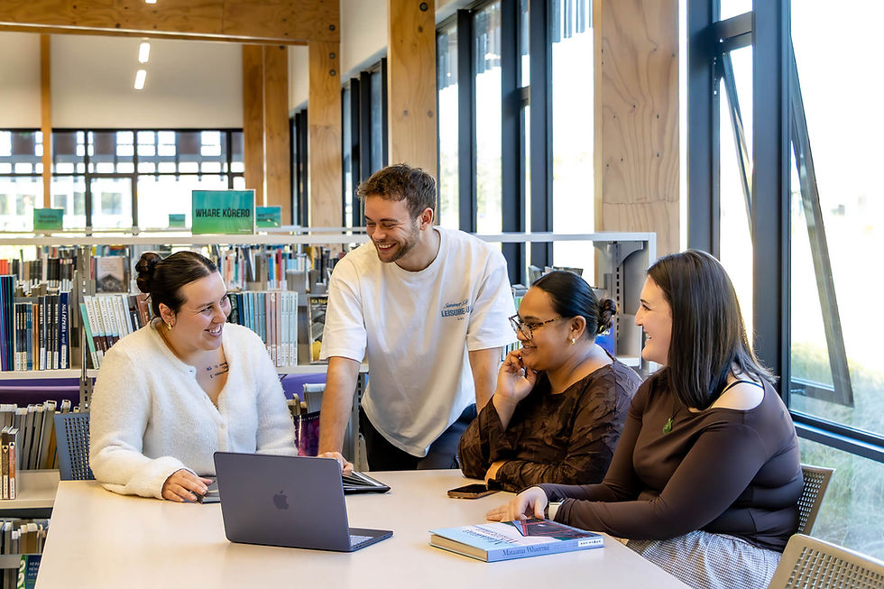 Diverse students smiling while collaborating in a library.
