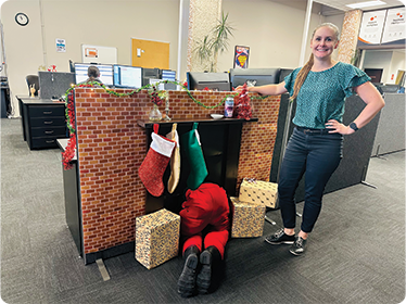Smiling woman by festive office desk, Santa by fireplace