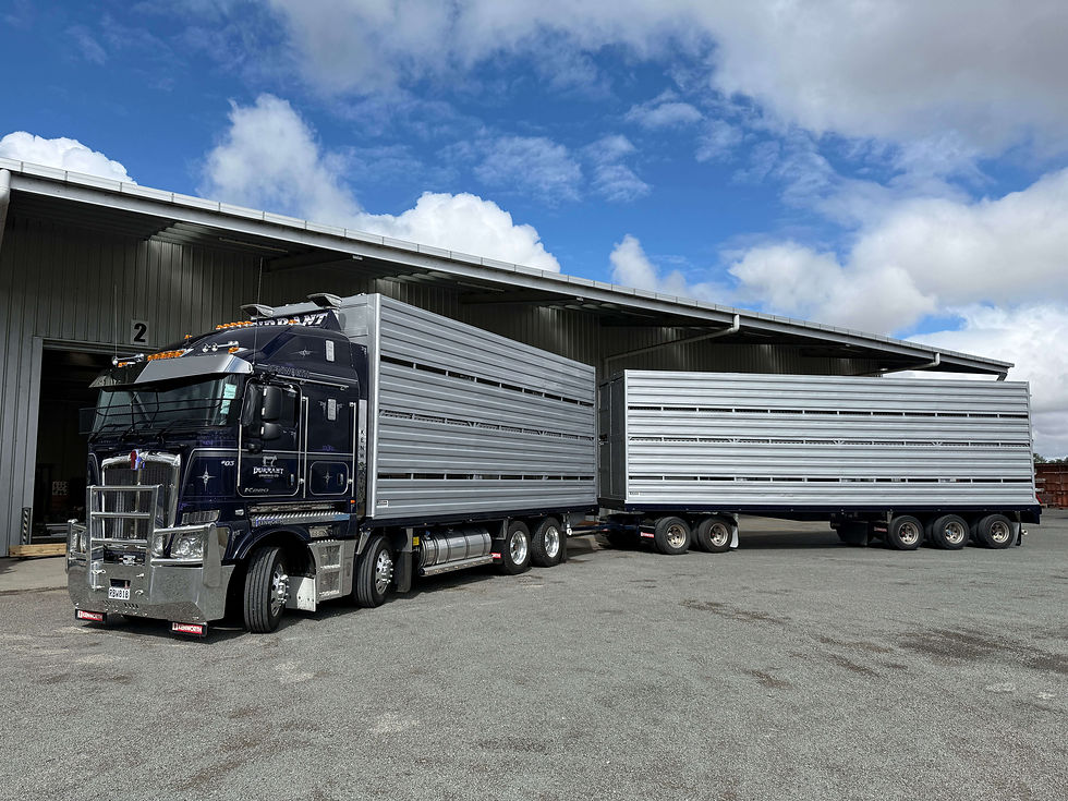 A large truck with two trailers parked outside a warehouse on a sunny day.