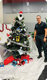 Man standing proudly beside a decorated Christmas tree
