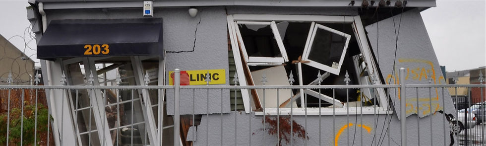 Damaged building with broken windows and visible text 203, LIKC, behind fence.