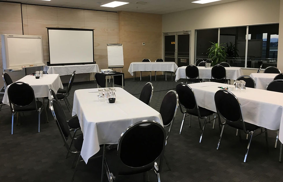 Conference room with white tables, black chairs, projector screen, flip charts.
