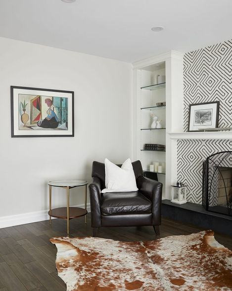 a living room with a black leather chair and a cowhide rug
