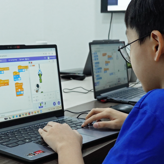 A student using Scratch's drag-and-drop coding blocks to create a game where the Kebbi robot sprite catches batteries to score points.