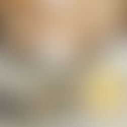 A woman peeling garlic, wearing rings, with a necklace on the table with a lemon.