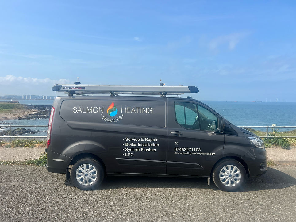 A black van with "Salmon Heating Services" branding is parked by the seaside on a sunny day