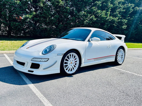 White Porsche 911 sports car with white wheels parked on asphalt.