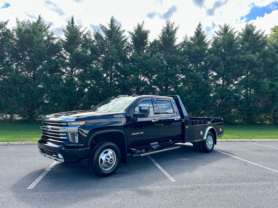 Black Chevrolet Silverado HD dually flatbed truck parked outdoors.
