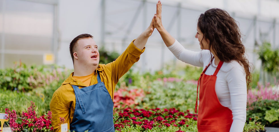 Woman florist helping young employee with Down syndrome in garden centre.jpg